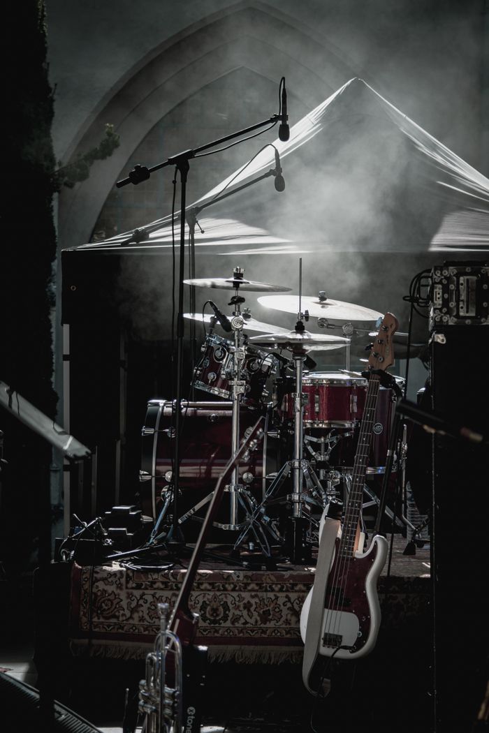 Dimly lit stage with drum kit and electric guitar ready for a live performance.